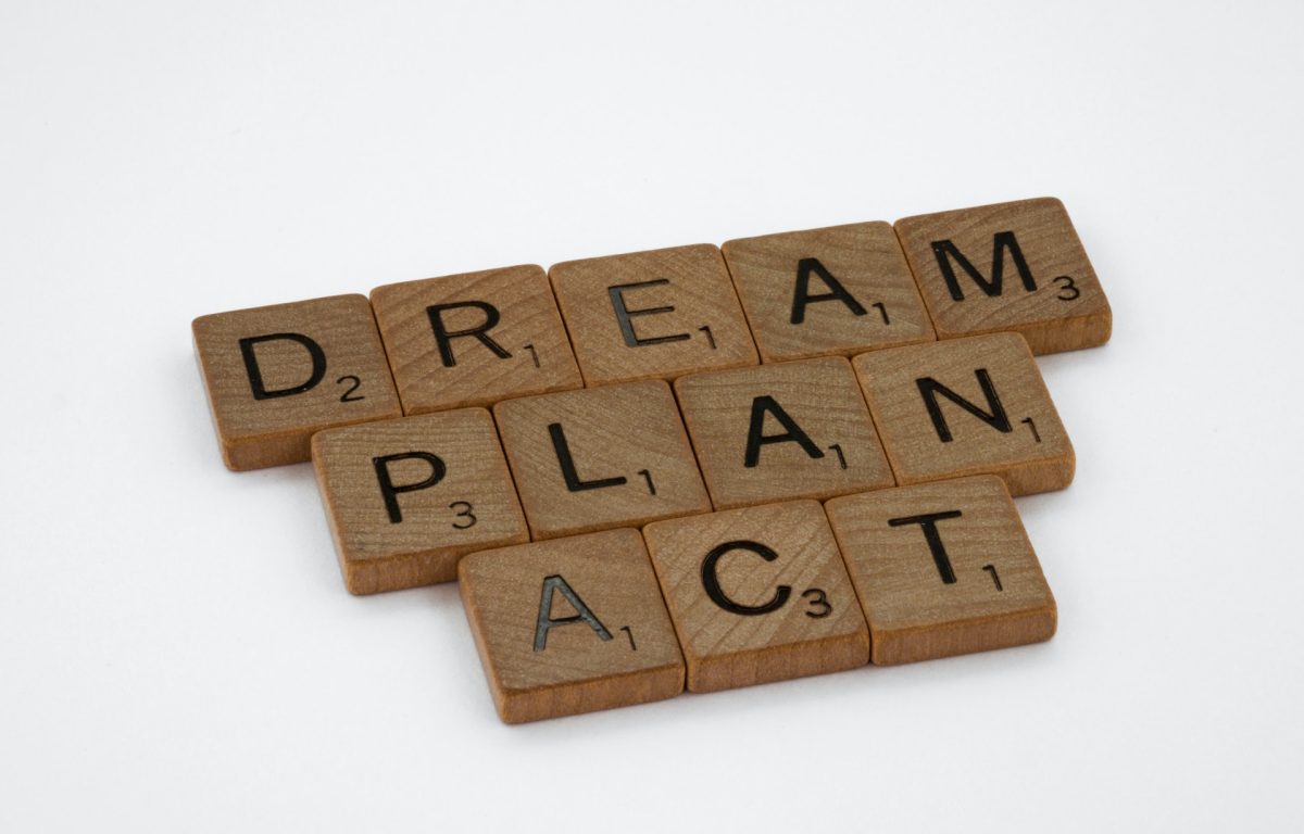Scrabble game tile letters in three lines spell out: Dream, Plan, Act.