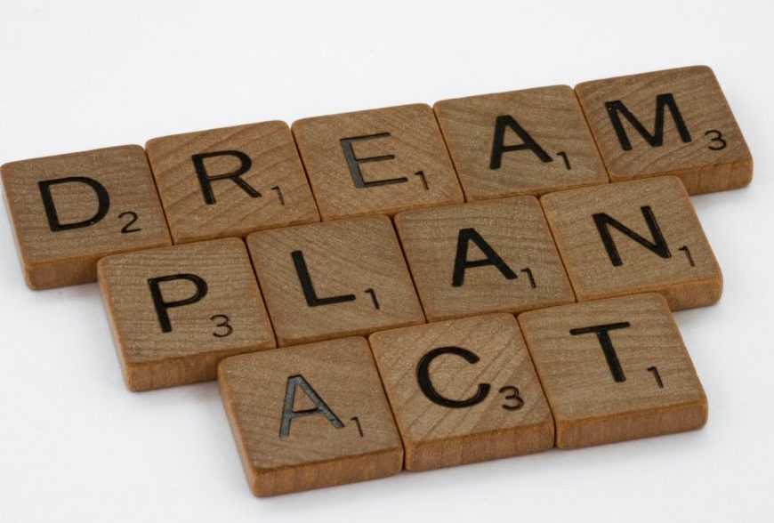 Scrabble game tile letters in three lines spell out: Dream, Plan, Act.