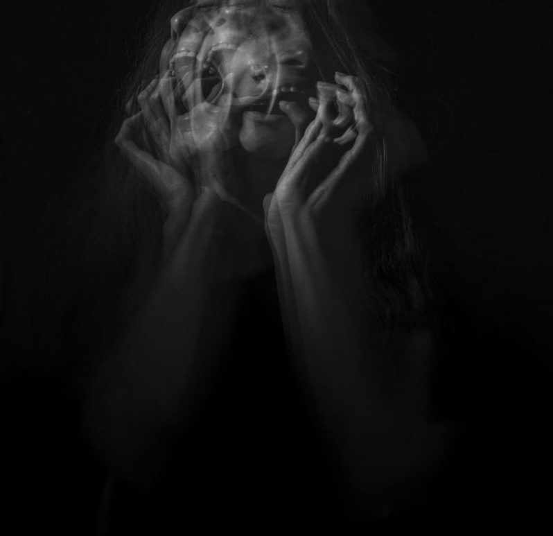 Black and white multi-exposure photograph of woman screaming in fear.