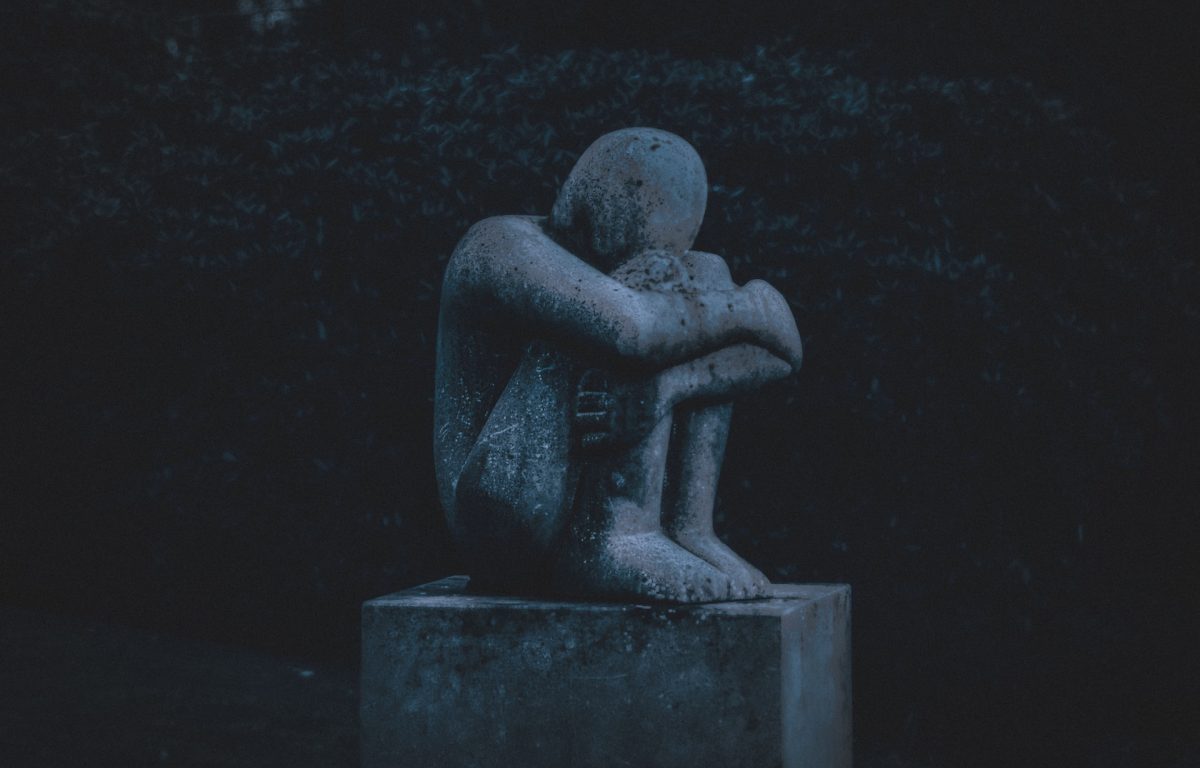 Stone sculpture of a person hugging their knees.