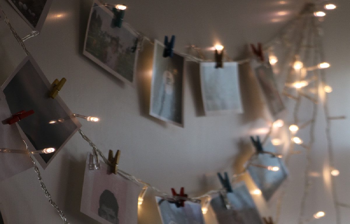 Clothes pin string lights with pictures hanging on a wall.