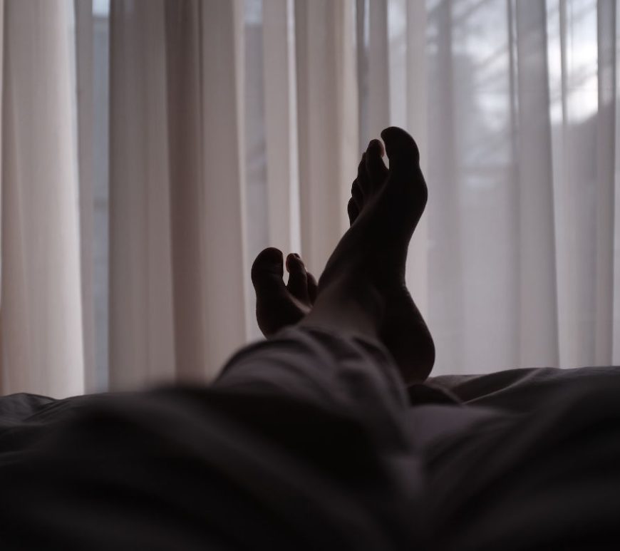 View of someone's legs and feet laying down.