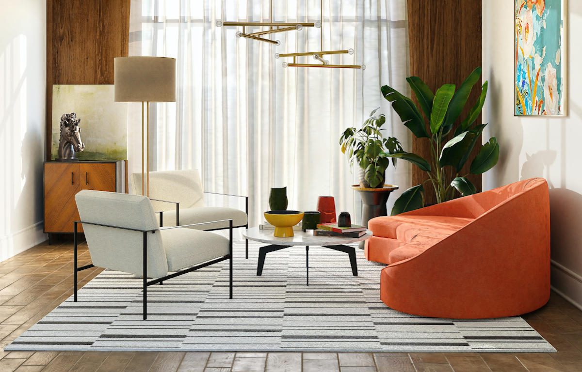 Living room with natural light coming through thin, white curtains, supplemented by a standing lamp and two hanging light fixtures. Wood floors with area rug create a contrast of texture. Couple of plants in the corner add a natural element. Bright coral-coloured couch across from two white chairs, and a round marble coffee table. Multiple vases, sculptures, and two paintings finish the room with splashes of colour.