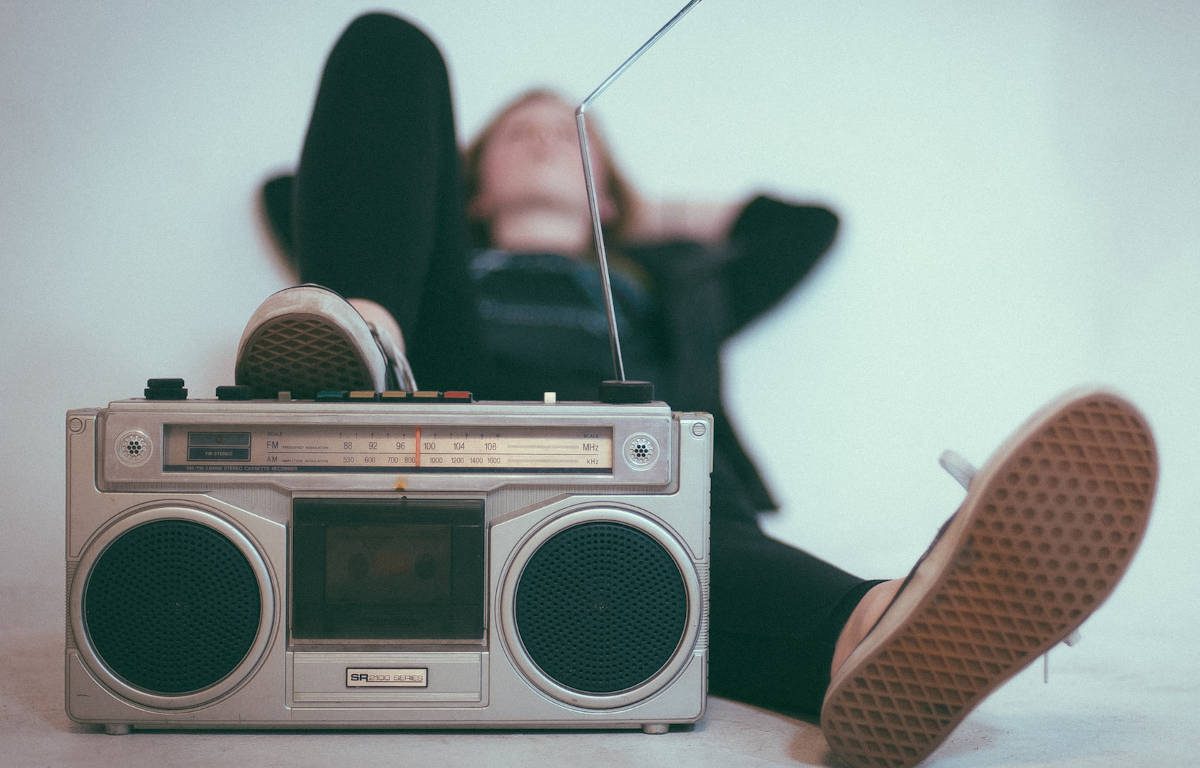 Person laying down listening to music with their right foot on the radio cassette player.