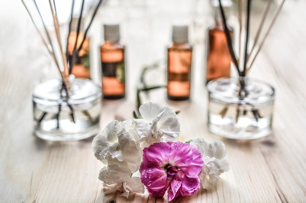 White and pink flowers with essential oil bottles and diffusers in the background.