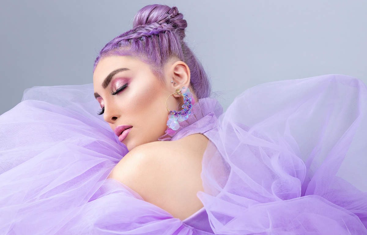 Woman with eyes closed dressed-up all in lavender colour - hair, make-up, jewellery, and dress.