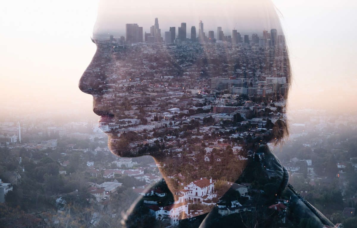 A young man's side profile as he gazes out into the distance, superimposed with a cityscape.