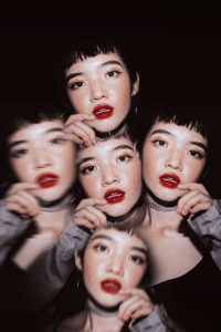 Prism lens effect of woman's portrait. She has bright red lipstick and black hair. Her face repeats four times around the middle one, some are blurrier than others.