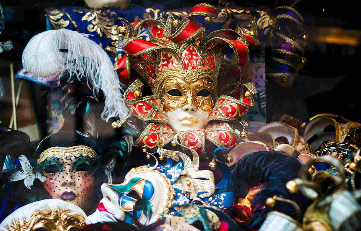 Pile of assorted masquerade masks with various embellishments and colours.
