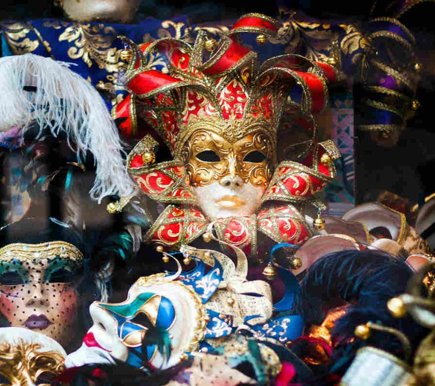 Pile of assorted masquerade masks with various embellishments and colours.