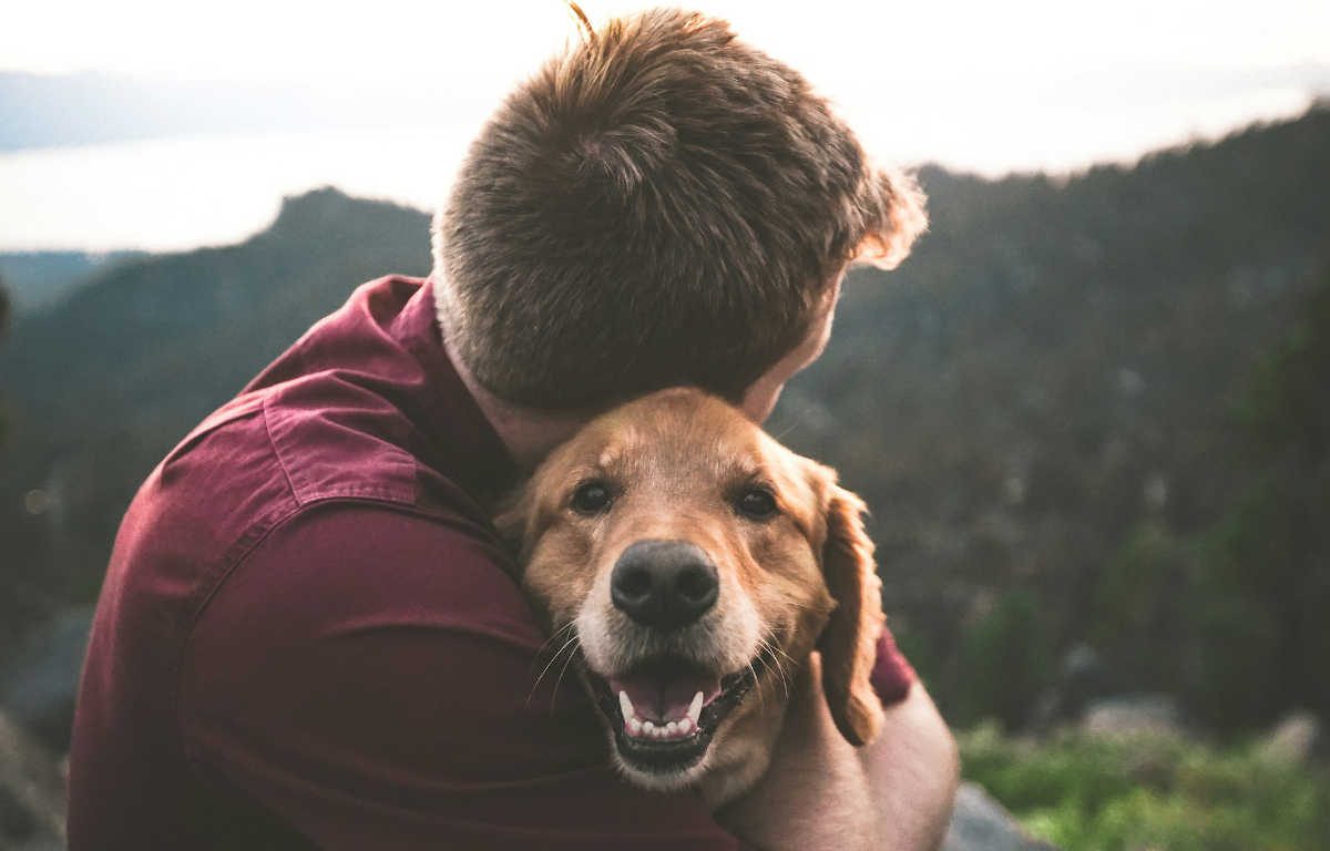 Man hugging his pet dog while outdoors.