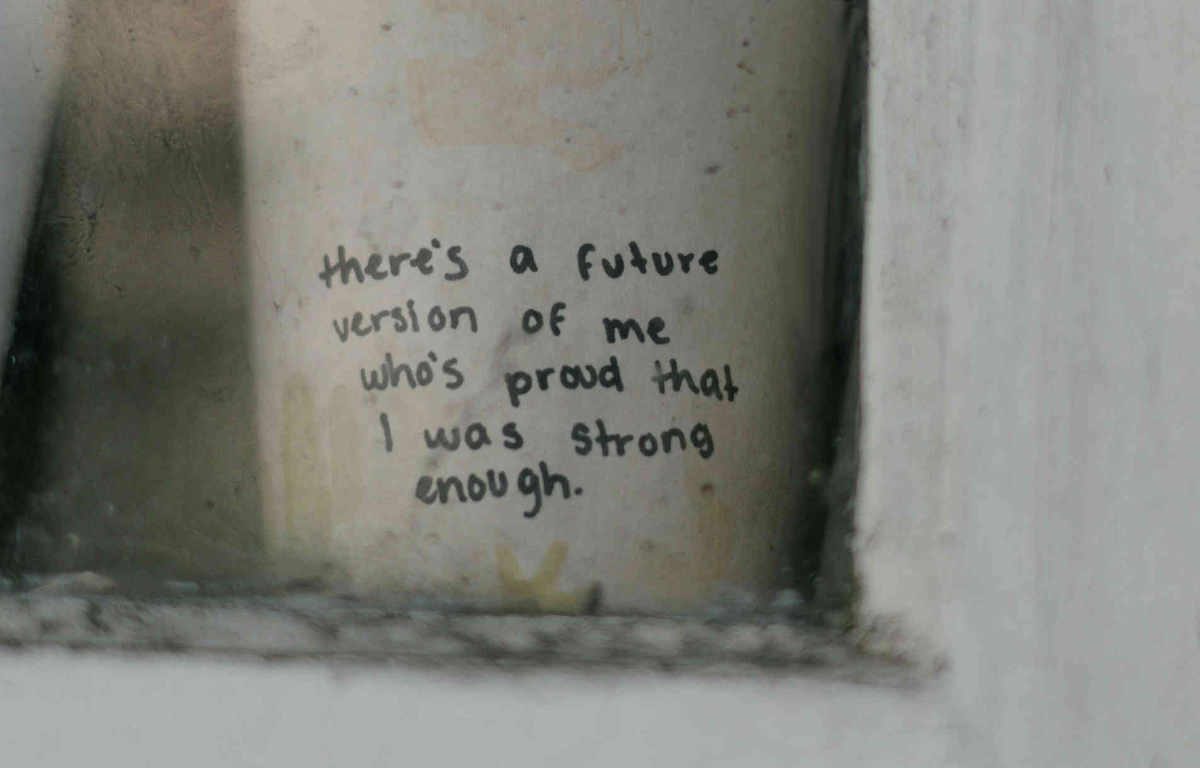 Text written in black marker on a coffee cup, on window ledge stating "there's a future version of me who's proud that I was strong enough."