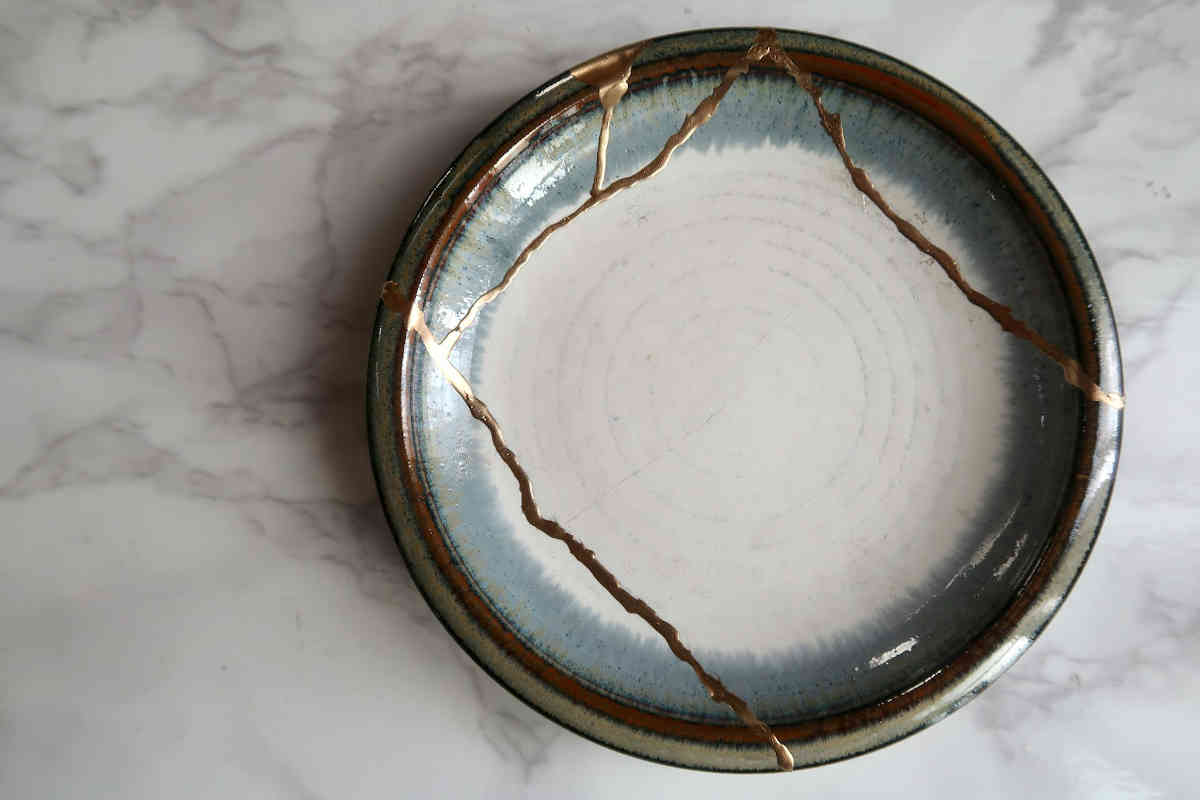 Broken ceramic plate mended with gold using traditional kintsugi technique.